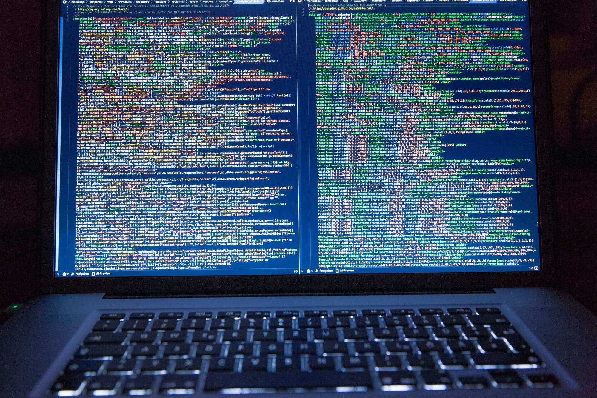 Laptop with code showing on a split screen in dark mode.