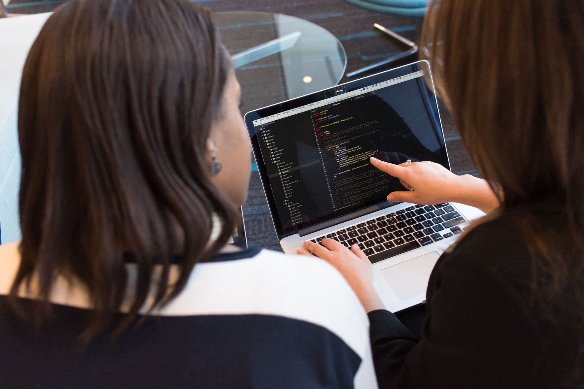 Two women looking at code on a laptop